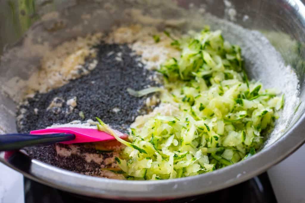 Folding poppy seed and grated zucchini into the sourdough muffin batter.