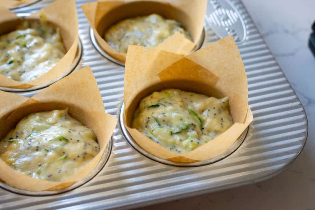 Sourdough discard muffin batter divided into mufifn tin lined with paper liners.