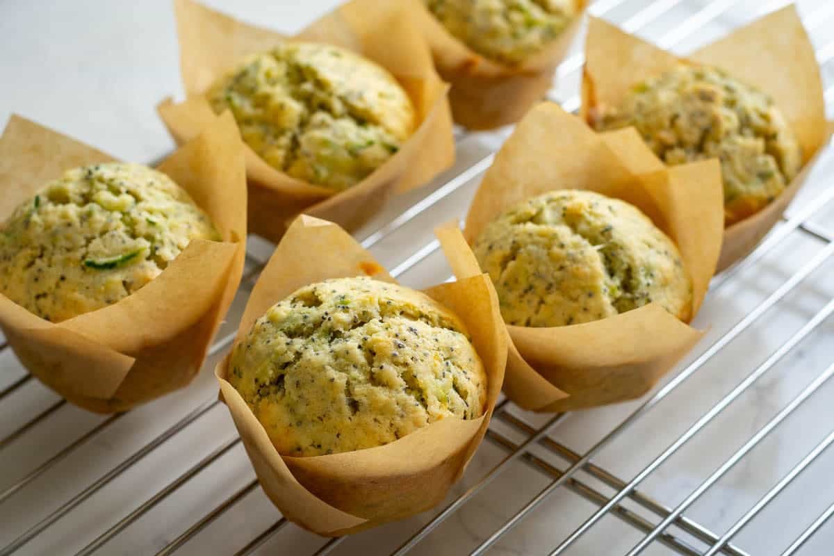 Lemon and poppy seed sourdough zucchini muffins cooling on a wire rack.