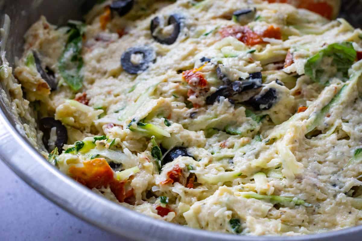 Mediterranean sourdough courgette quick bread batter mixed in a large metal mixing bowl.