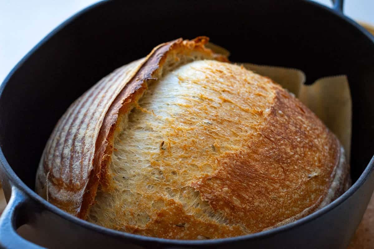 Depp golden brown sourdough with an ear in a dutch oven.