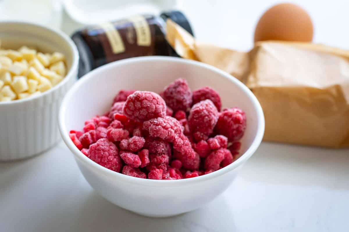 Frozen raspberries in a small white bowl.