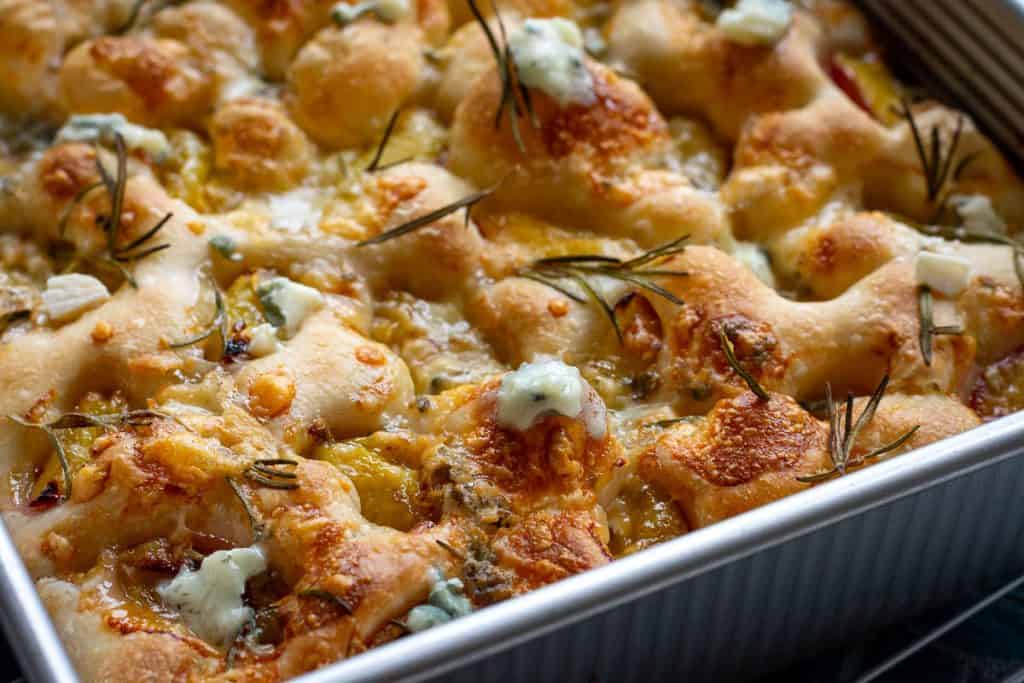 Baked gorgonzola and plum sourdough focaccia in a baking tray.
