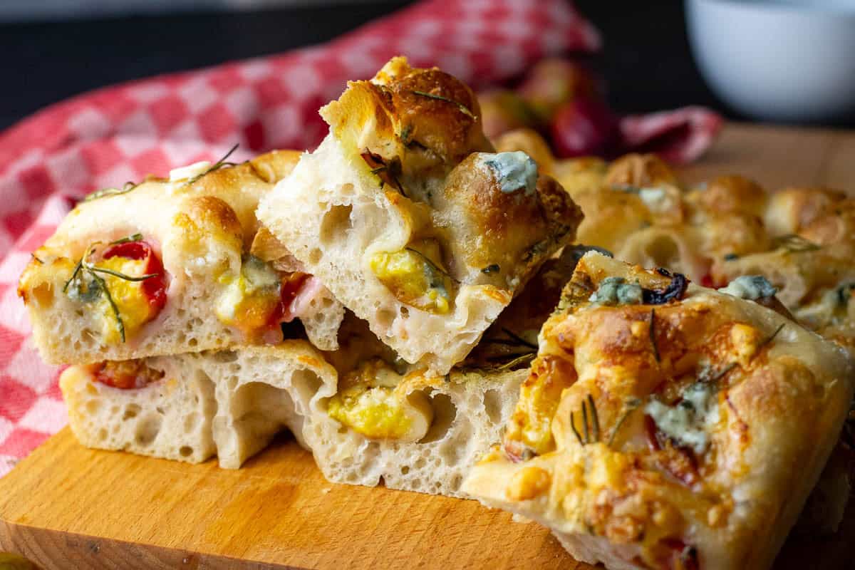 Plum and Gorgonzola Sourdough Focaccia squares on a wooden board.