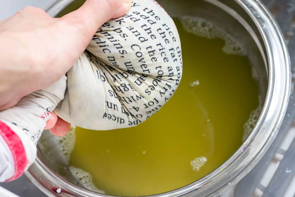 Squeezing excess moisture from zucchini and red onion placed in a clean kitchen towel.