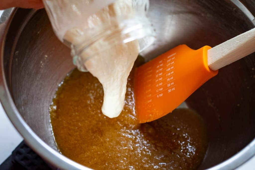 Pouring sourdough discard into the cookie dough.