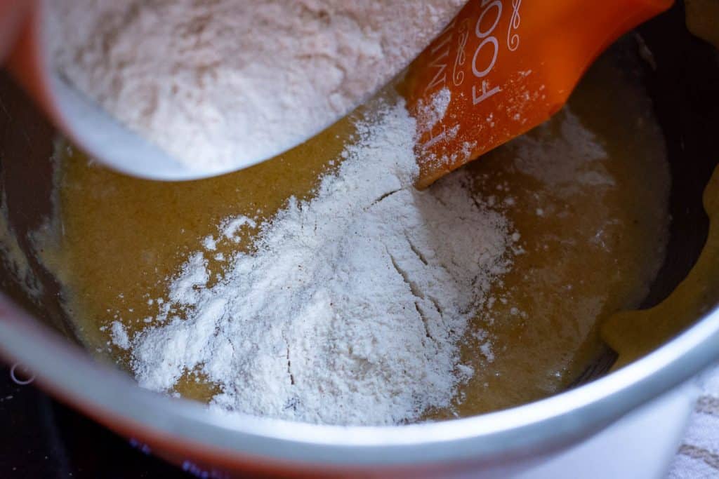 Dry ingredeints being added to the wet ingredients for the sourdough cookies.