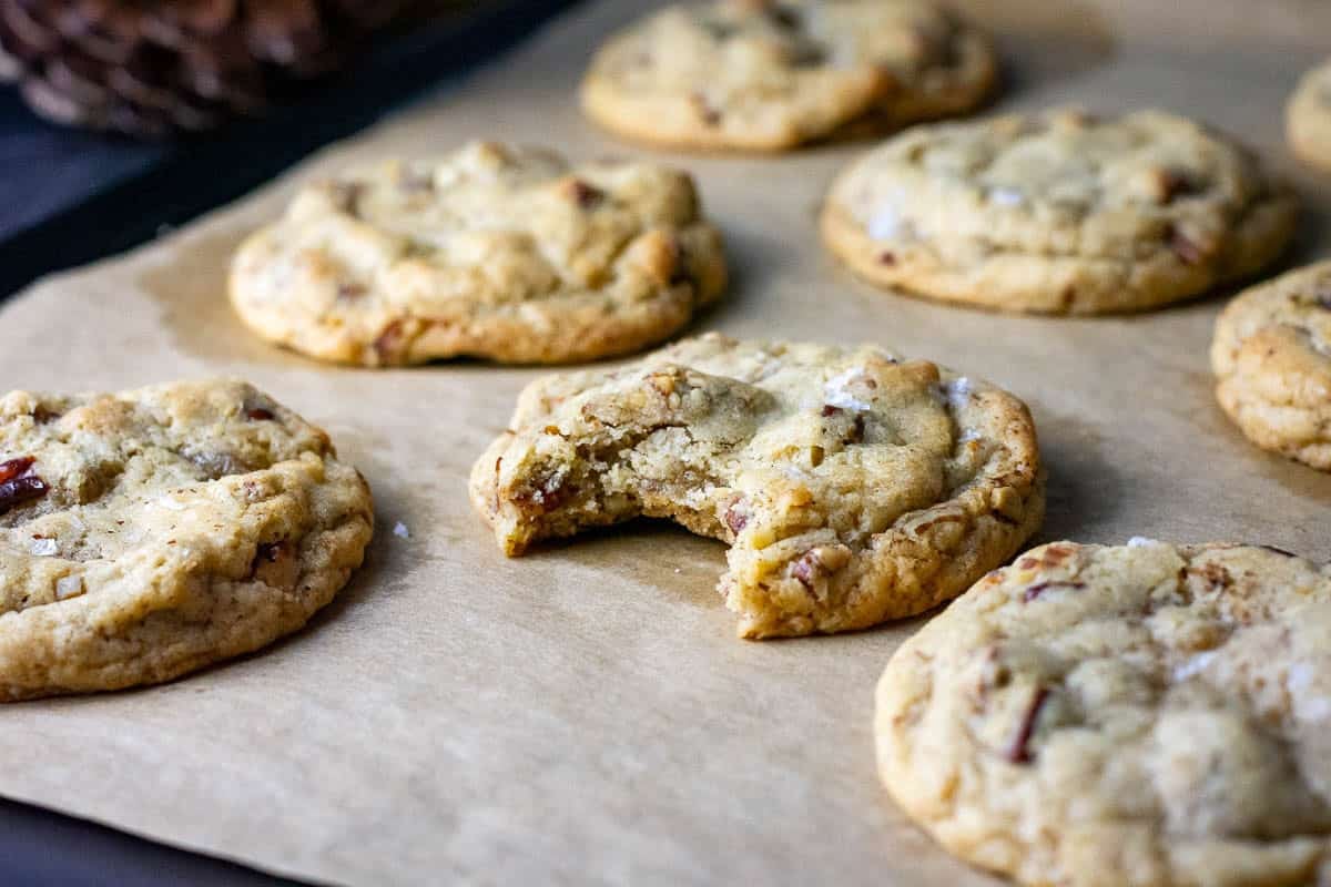 Butter pecan sourdough discard cookies on a baking tray with one missing a bite.