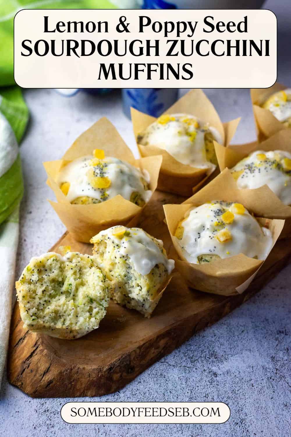 Sourdough Zucchini Muffins with lemon and poppy seeds on a wooden board with one torn in half exposing moist crumb. Pin for Pinterest.