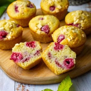 Raspberry and White chocolate sourdough discard muffins on a wooden board with one cut in half.
