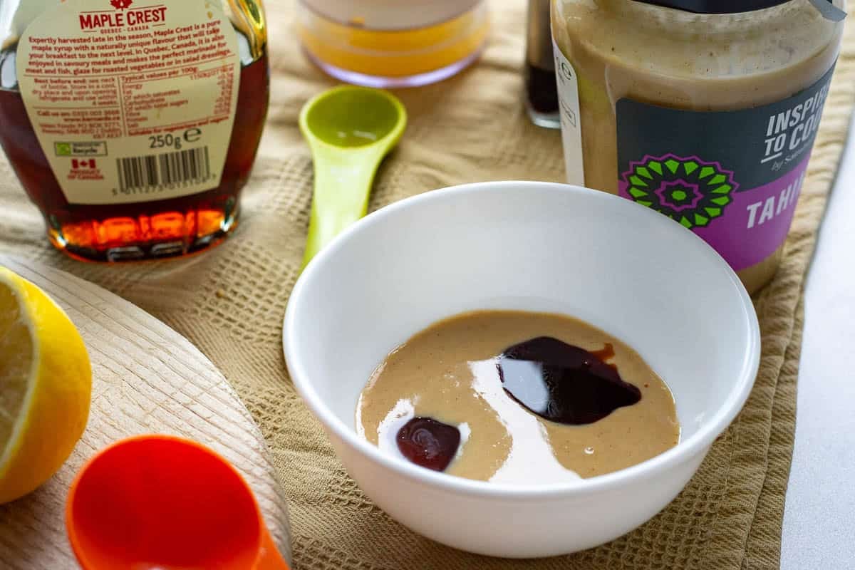Tahini drizzle ingredeints in a small white bowl before being mixed.