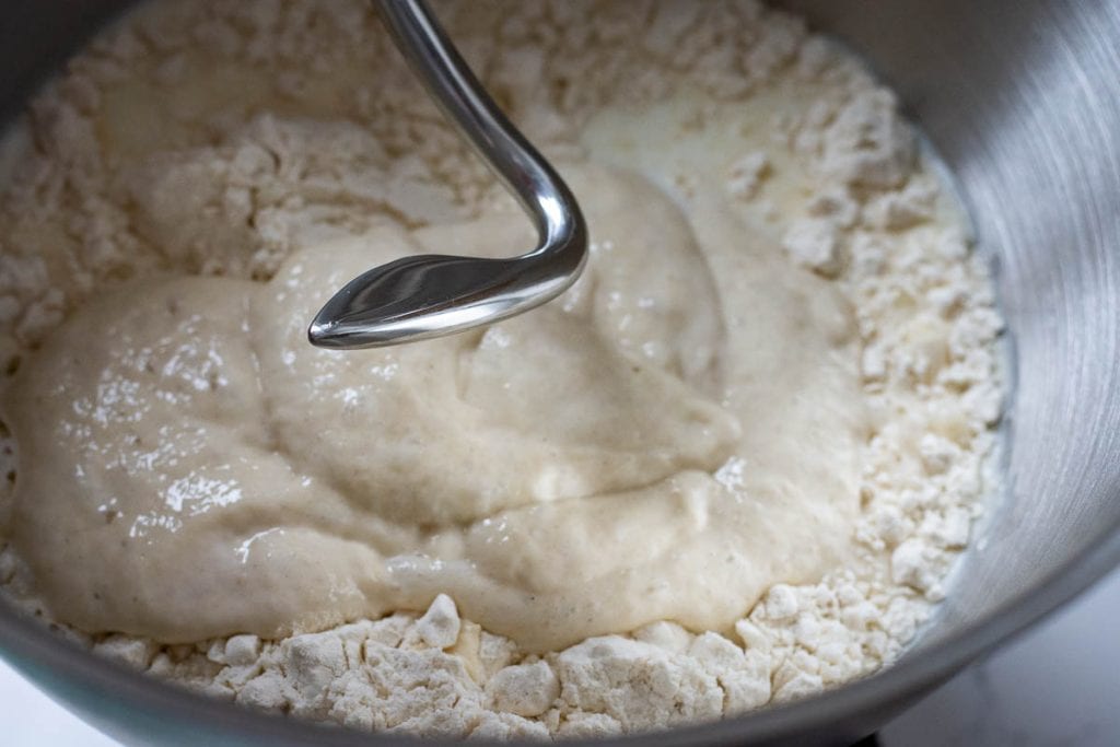 Mixing flour, sourdough starter and milk in a stand mixer fitted with a dough hook attachment.