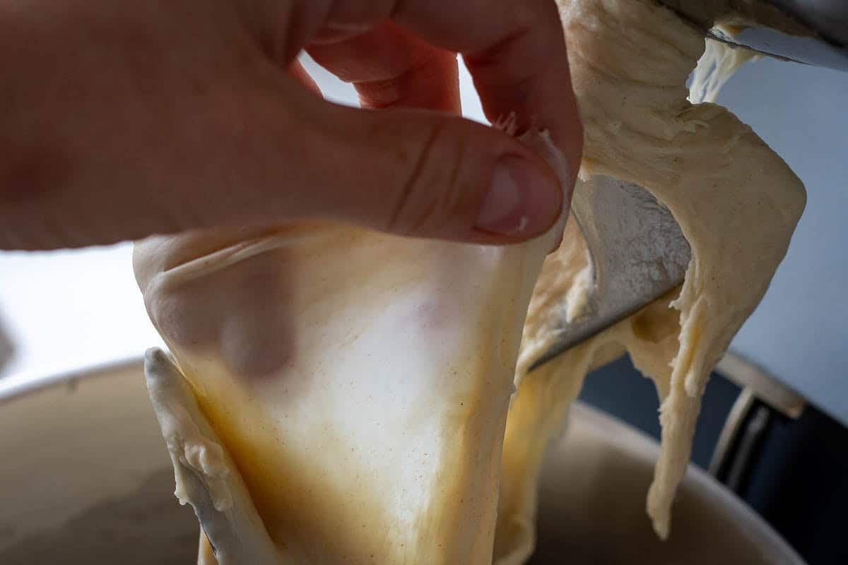 Checking if sourdough passes windowpane test by stretching the dough out thinly without it tearing.