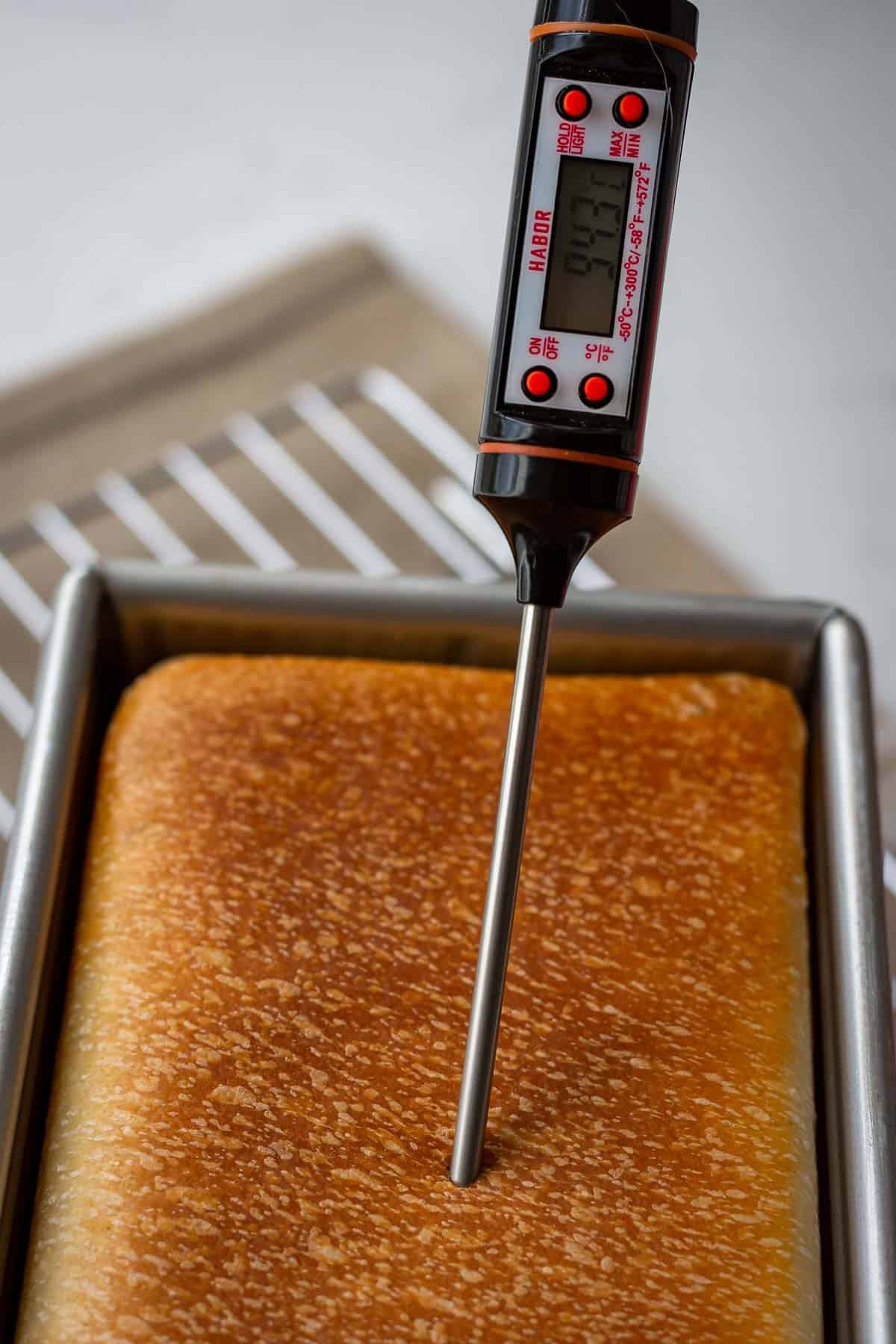 Kitchen thermometer inserted into the centre of a sourdough pullman loaf.
