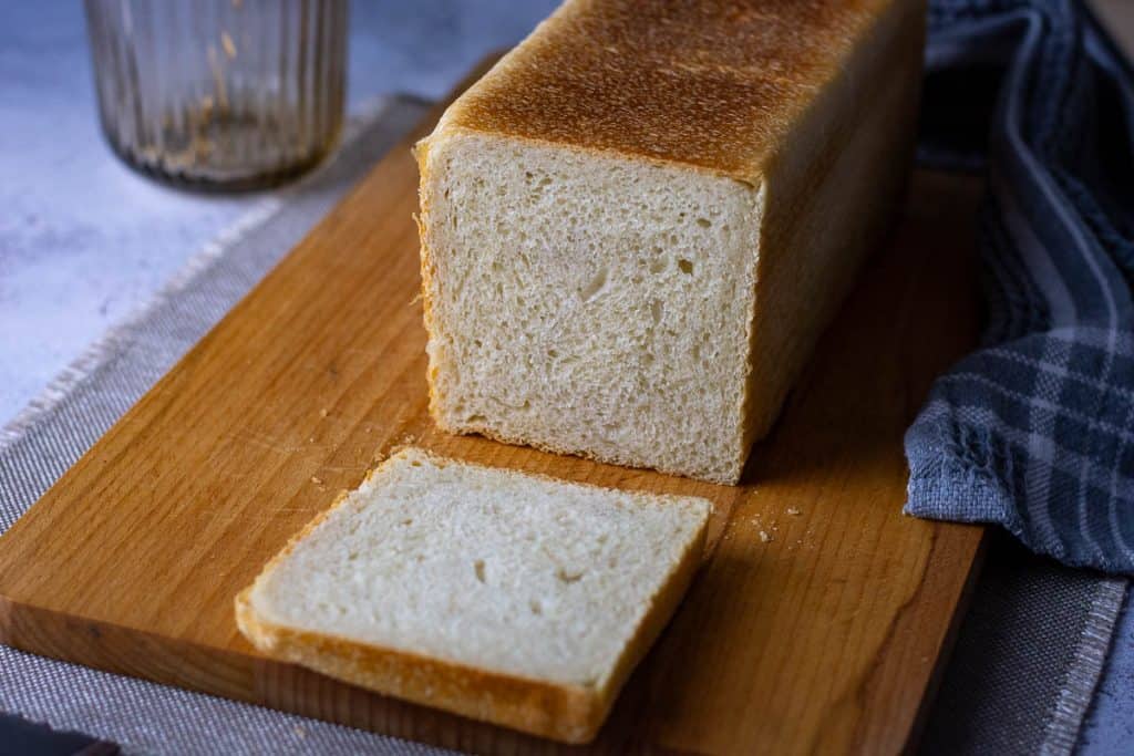 Sliced sourdough pullman loaf on a wooden board.