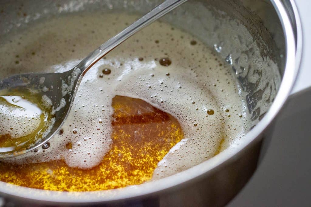 Brown butter in a small pan with a spoon in it.