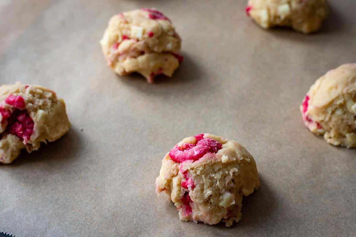 Frozen sourdough cookie dough balls on a large baking sheet lined with parchment paper.