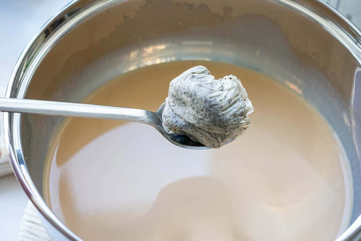 Earl Grey tea bags being taken out of milk after infusing the milk.