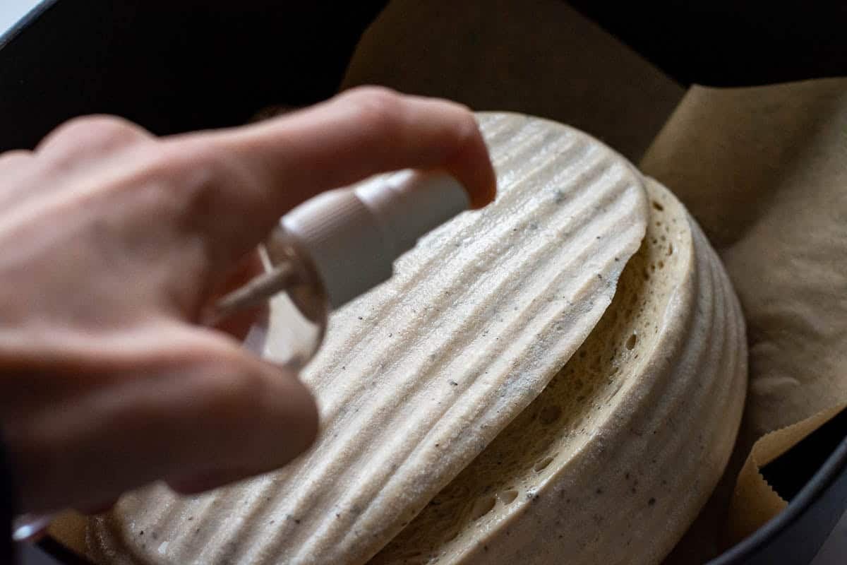 The surface of the sourdough bread being spritzed with water.