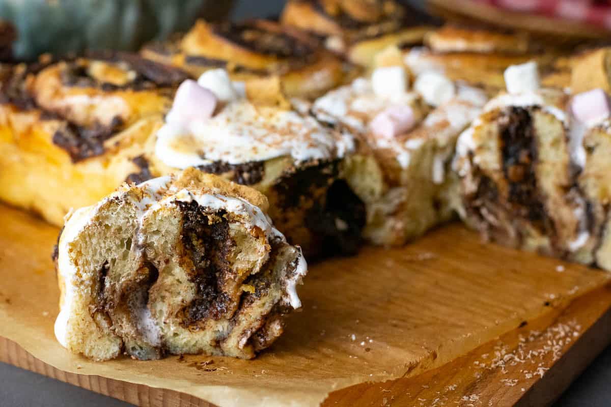 A sourdough s'mores roll cuut in half with the rest of the batch in the background.