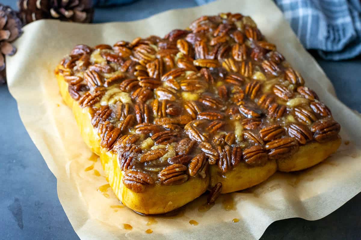 Sourdough sticky buns with mapel pecan top inverted on a piece of parchment paper.