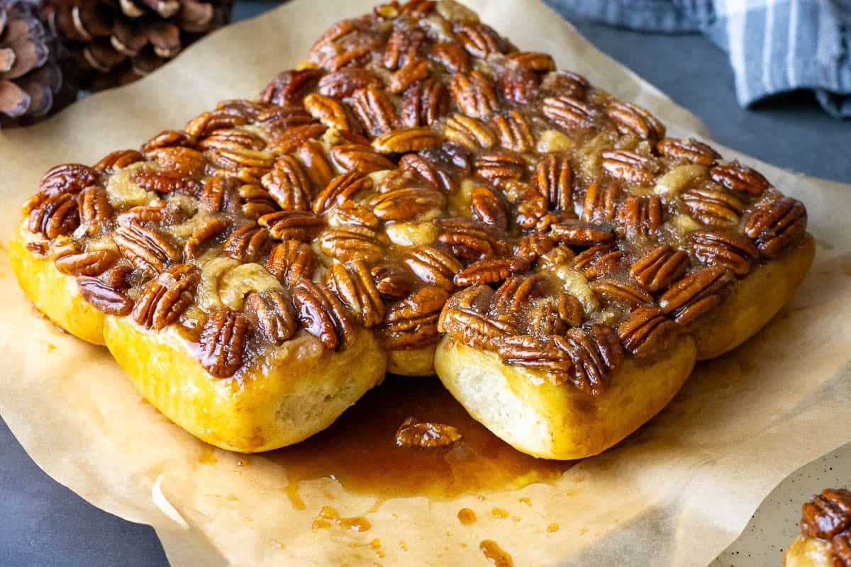 A batch of sourdough maple pecan rolls with one missing.
