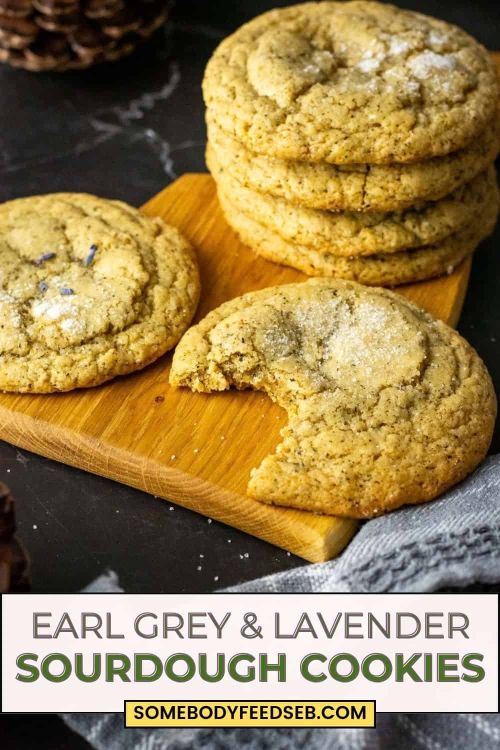Stacks of Lavender and Earl Grey Sourdough Cookies on a wooden board with one cookie already bitten into. Pin for Pinterest.