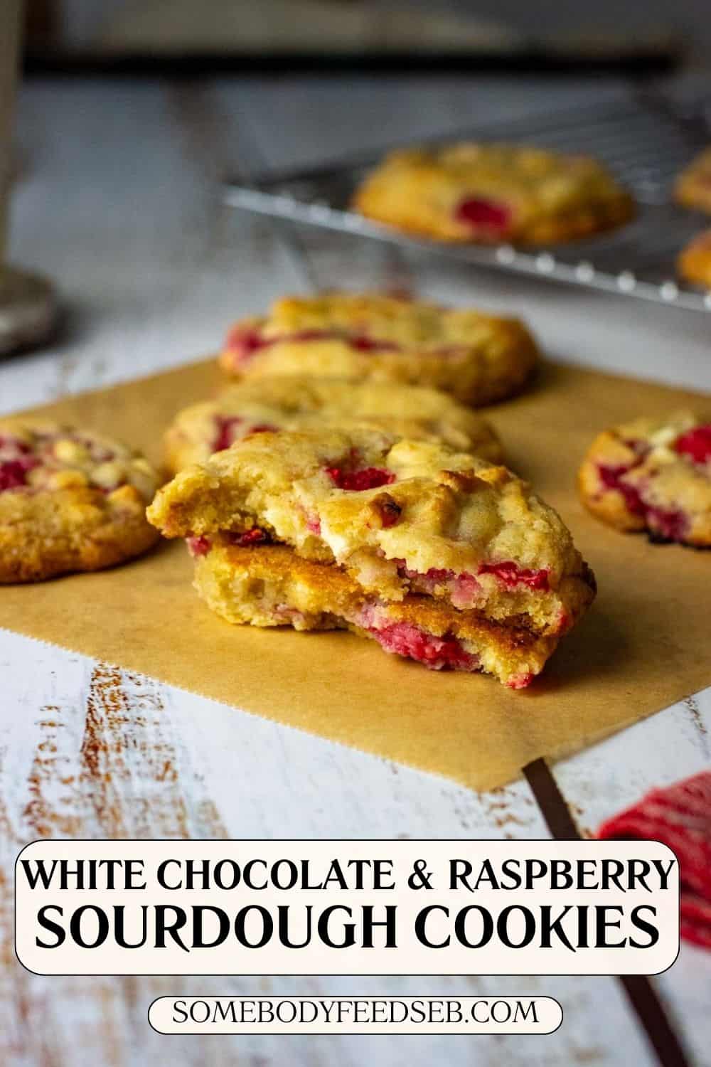 Raspberry and White chocolate sourdough cookie broken in half on a piece of parchment paper. Pin for Pinterest.