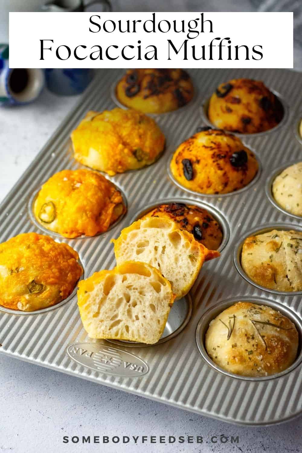 A muffin pan with 12 sourdough focaccia muffins with three different toppings, one muffin is cut in half showing airy interior. Pin for Pinterest.
