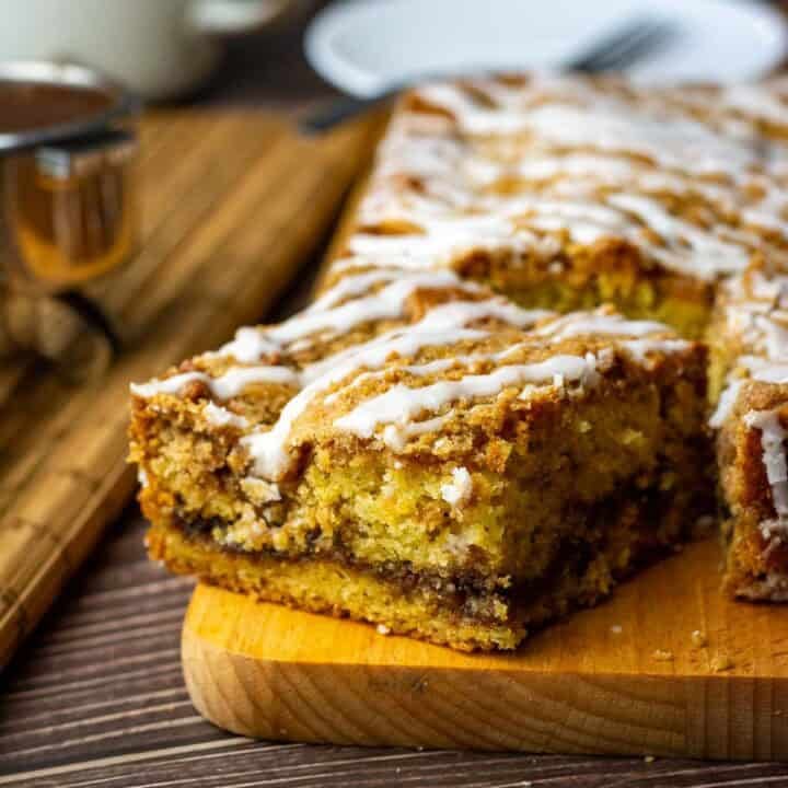 A piece of sourdough coffee cake on a wooden board showing a cinnamon layer in the middle.