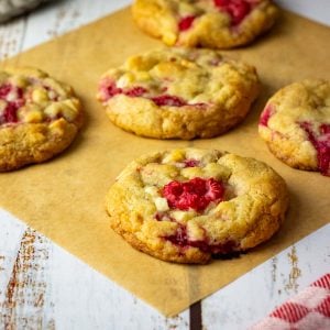 Baked sourdough raspberry and white chocolate sourdough cookies on a piece of parchment paper.