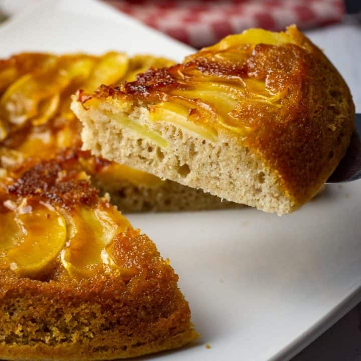 A slice of stovetop sourdough apple cake made in a frying pan being cut.