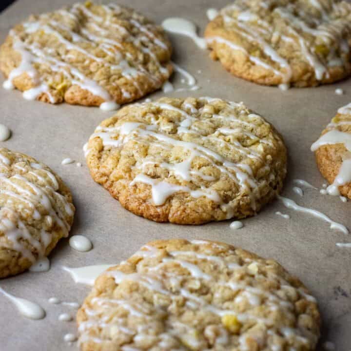 Sourdough apple cookies with oat crumb topping and sugar glaze on a baking sheet lined with parchment paper.