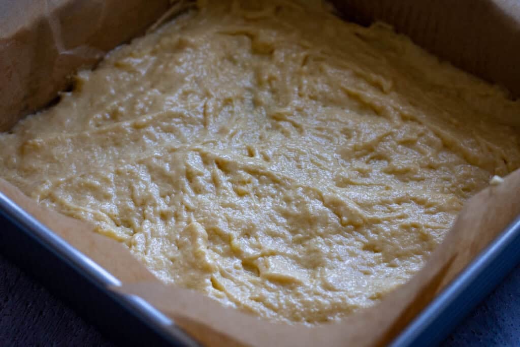 Half of the sourdough cake batter in a square baking pan.