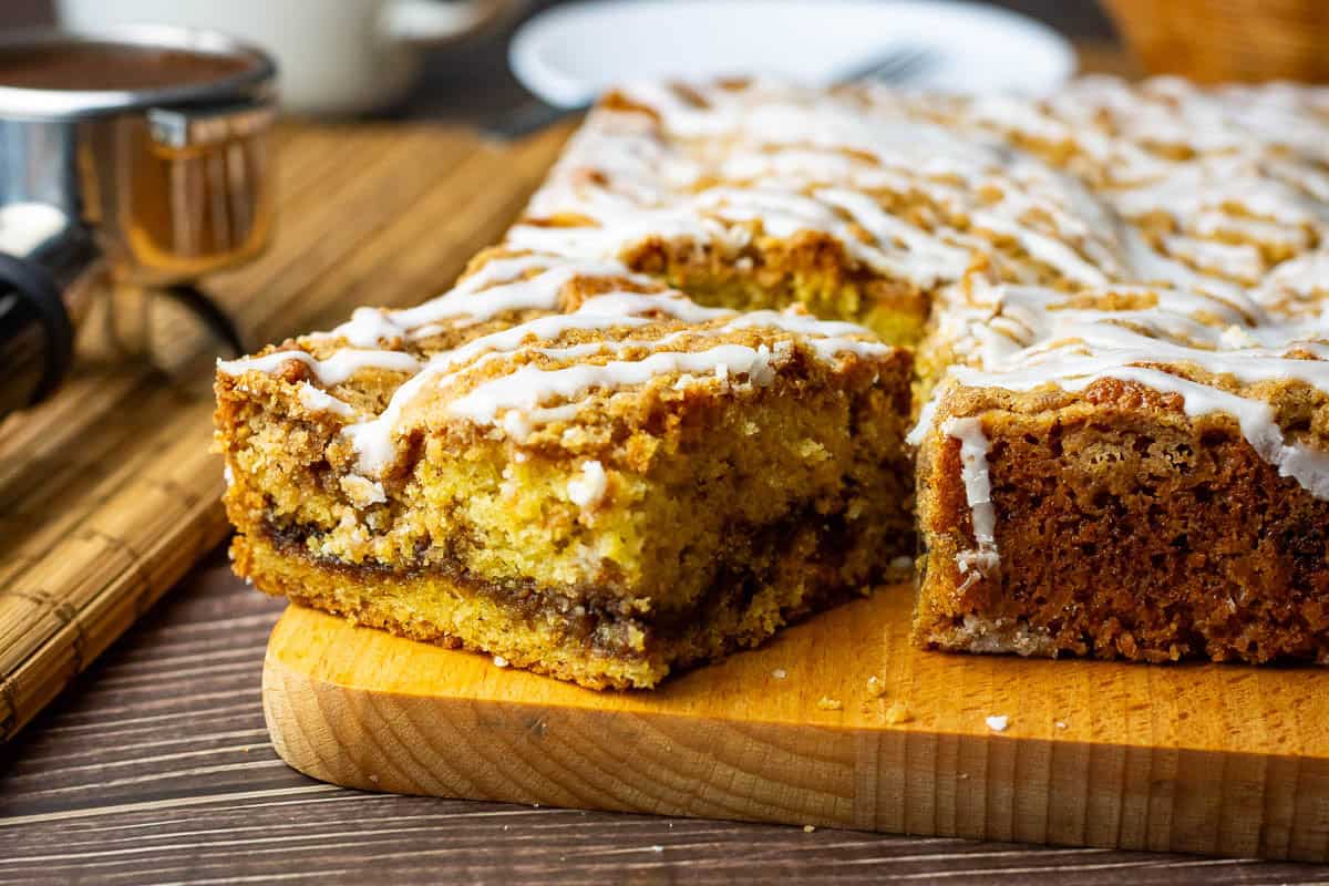 A piece of sourdough coffee cake on a wooden board showing a cinnamon layer in the middle.