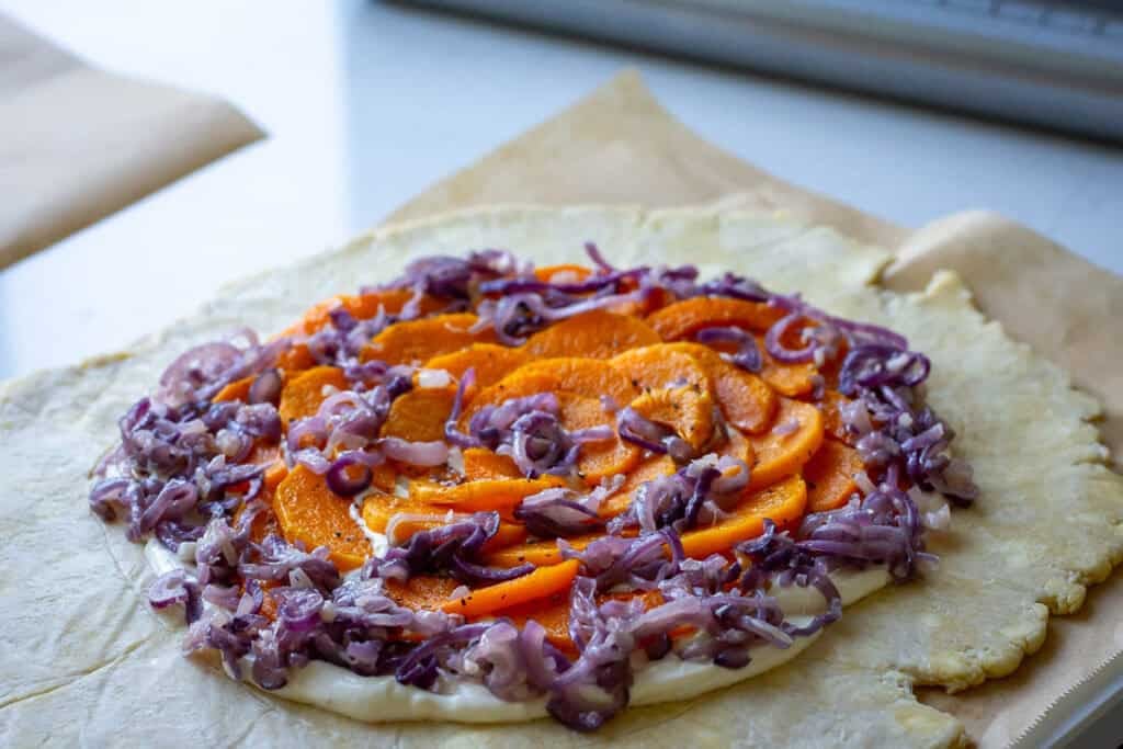 Sourdough pastry topped with butternut squash and red onions with cream cheese underneath.