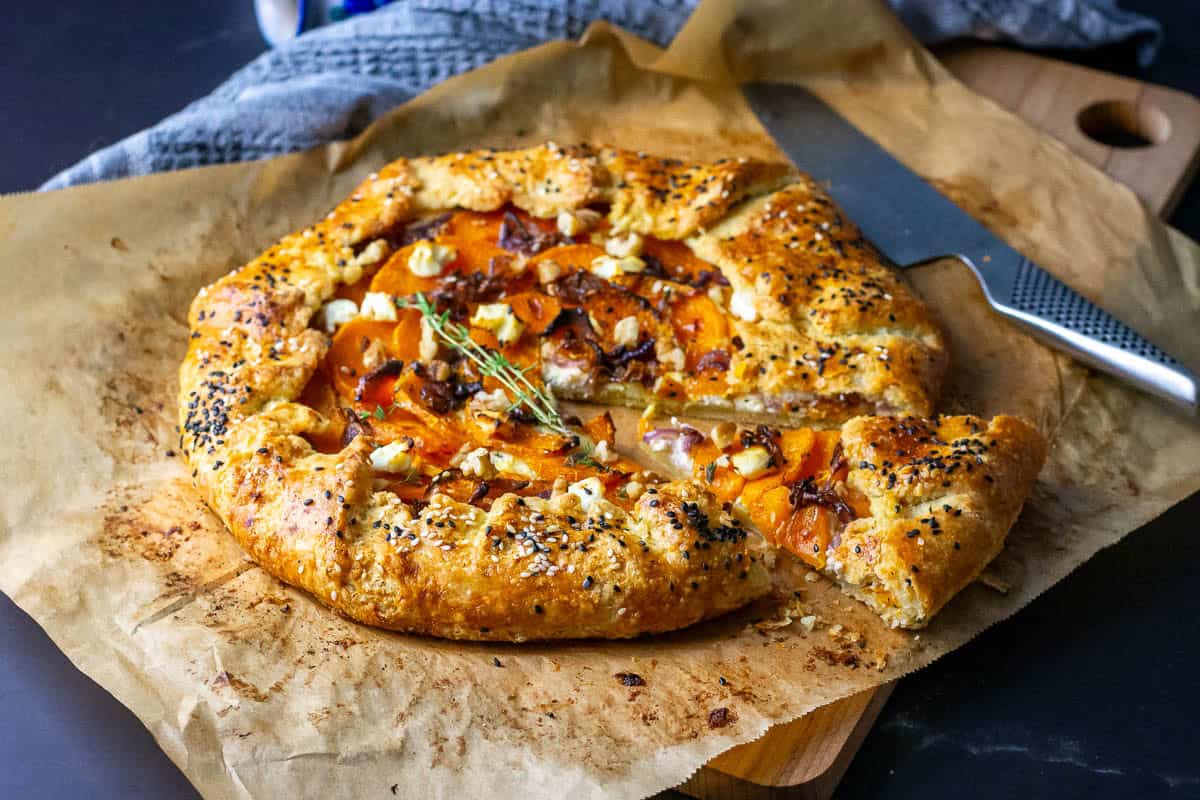 Butternut Squash Sourdough Galette with one slice cut on a piece of parchment paper.