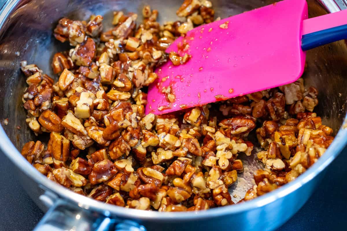 Pecans being coated in maple caramel.