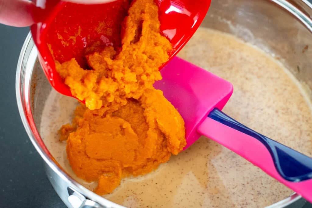 Adding pumpkin puree to the spiced milk mixture.