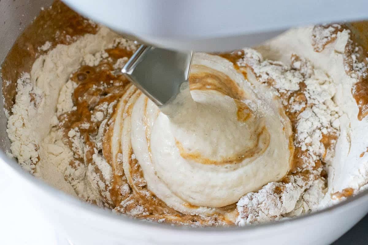 Sourdough being mixed in a stand mixer fitted with a dough hook attachment.