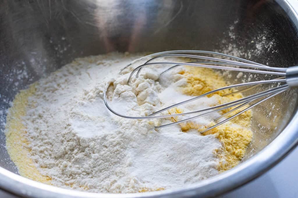 Mixing dry ingredients in a large metal bowl with a balloon whisk.