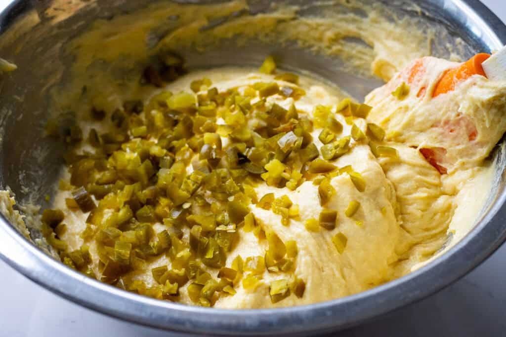 Chopped pickles jalapeno peppers on top of the cornbread batter.
