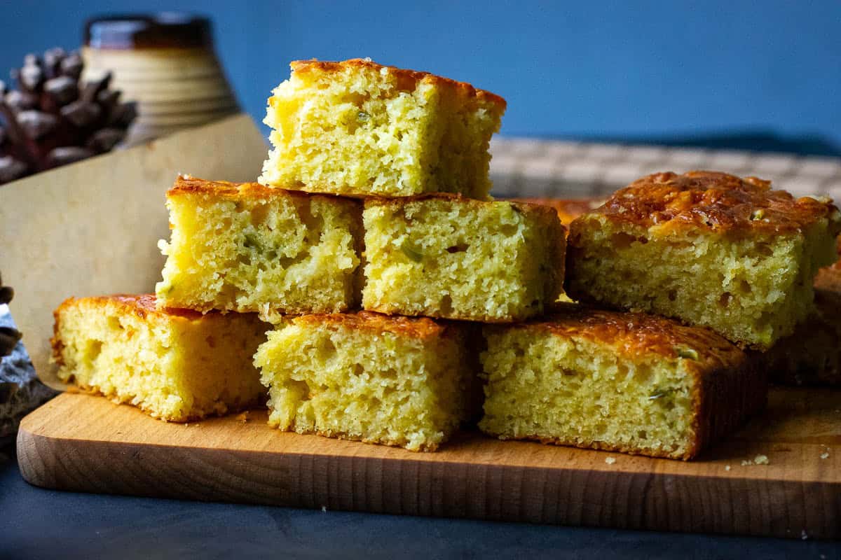 A stack of sourdough cornbread squares on a wooden board.