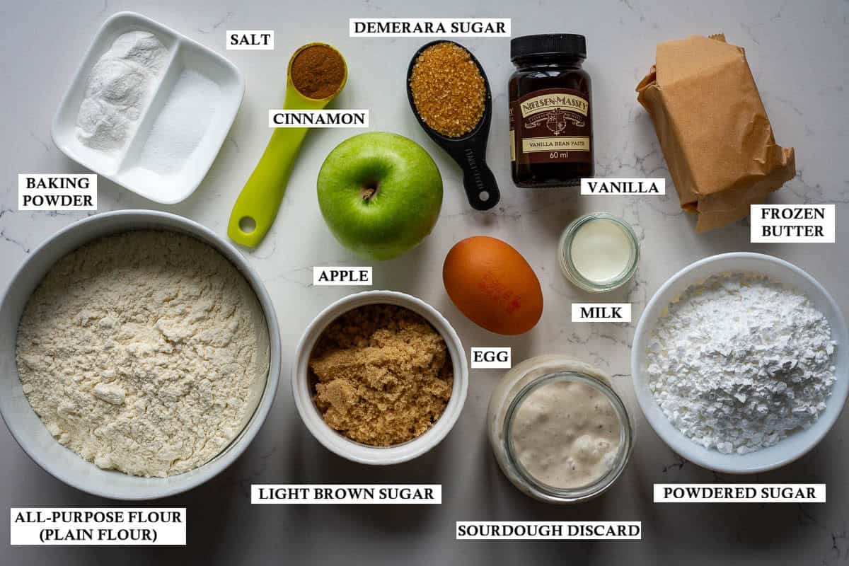 Labelled ingredients for sourdough discard apple scones on a light kitchen worktop.