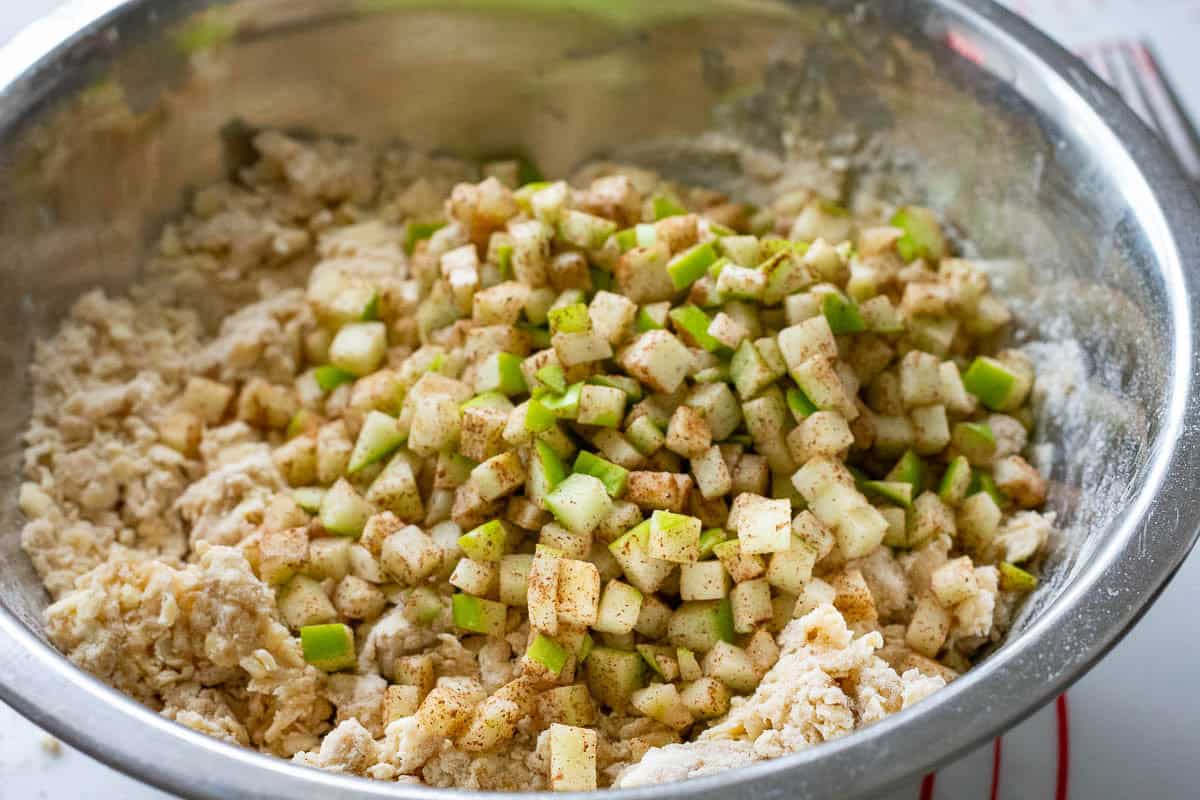 Cinnamon apples being stirred into the flour and butter mixture.