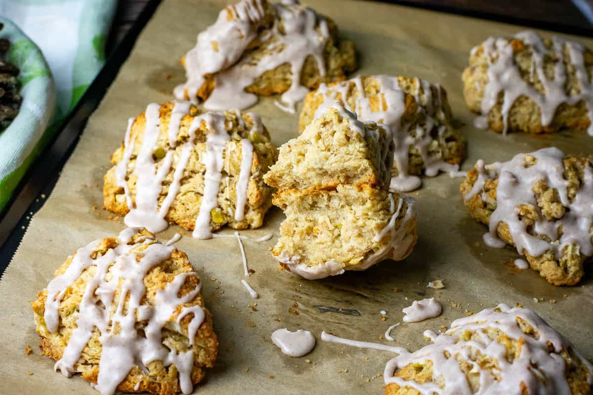 A baking sheet full of glazed apple sourdough scones with one broken in half.