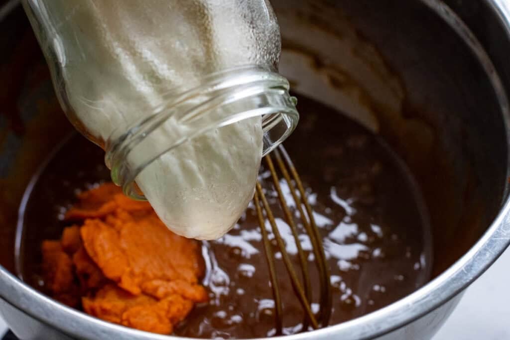 Pouring sourdough discard into the blondie batter mixture.