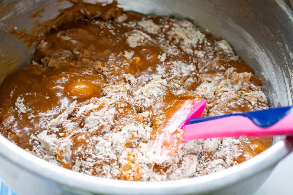 Folding dry ingredeints into the sourdough blondie batter with a rubber spatula.