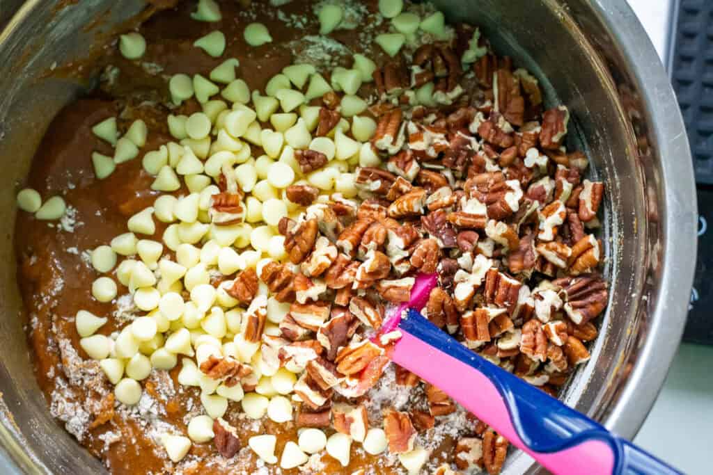 Folding white chocolate chips and pecans in to the chai-spiced blondie batter.