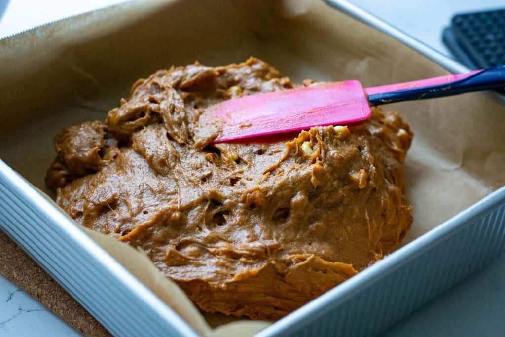Spreading sourdough discard blondie batter into the corners of the baking pan.